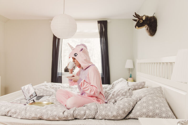 playful woman in unicorn costume in bedroom